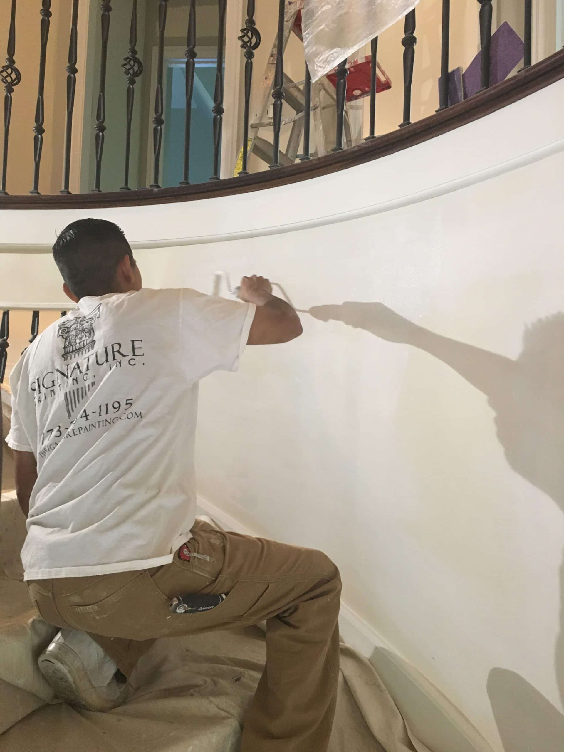 Painter painting the side of wall on the staircase
