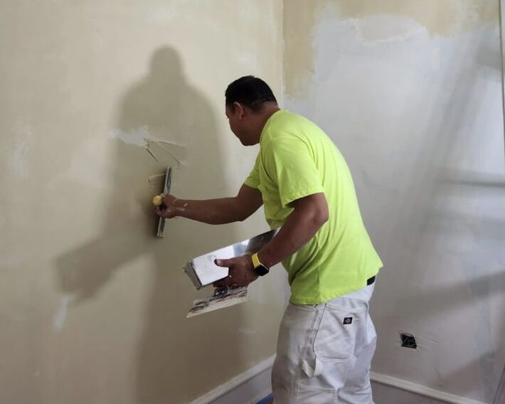 A man in neon lime adding paint to the wall